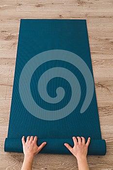 Woman rolling out her yoga mat in a studio