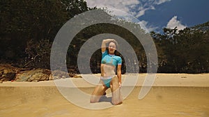 Woman rolling on the sandy beach, enjoying her vacation on a tro