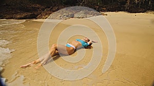 Woman rolling on the sandy beach, enjoying her vacation on a tro