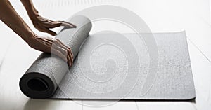 Woman rolling up exercise mat and preparing doing yoga or fitness. Hands and mat closeup.