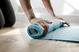 Woman rolling yoga mat after finishing with the exercise