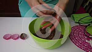 A woman rolls balls with her hands from a mass made from crumbs from cookies and cocoa, with the addition of butter. Makes blanks