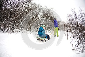 A woman rolls a boy on a sled