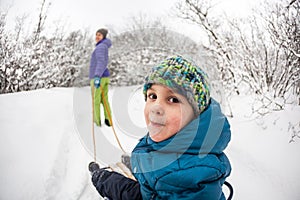 A woman rolls a boy on a sled