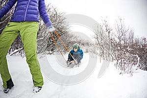 A woman rolls a boy on a sled