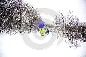 A woman rolls a boy on a sled