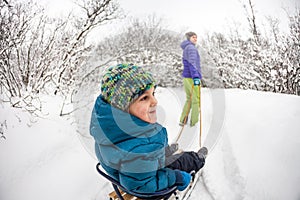 A woman rolls a boy on a sled