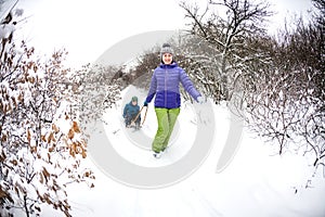 A woman rolls a boy on a sled