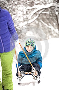 A woman rolls a boy on a sled