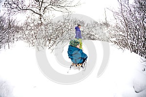 A woman rolls a boy on a sled