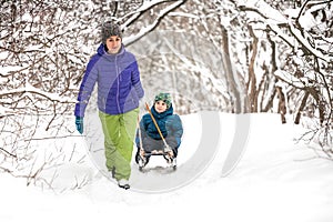 A woman rolls a boy on a sled