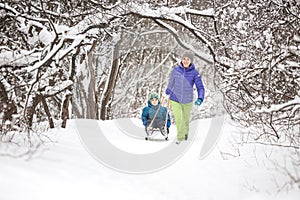 A woman rolls a boy on a sled