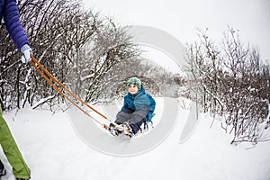 A woman rolls a boy on a sled