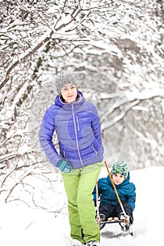 A woman rolls a boy on a sled