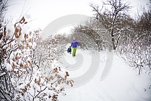 A woman rolls a boy on a sled