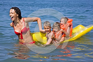 Woman rolls children on an inflatable mattress