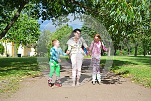 Woman rolls children`s hands on roller skates in the Park in the