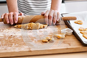 Woman rolls dough with rolling pin on the table in the kitchen. Gluten free flour cookies. Homemade healthy eating.