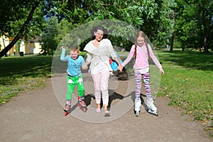 A woman rolls her hands on the cheerful children on roller skate