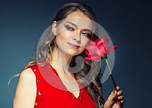 Woman with rose flower. Beauty female portrait with beautiful rose flower and salon hairstyle over gay blue background blonde hair