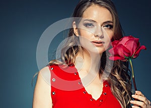 Woman with rose flower. Beauty female portrait with beautiful rose flower and salon hairstyle over gay blue background blonde hair