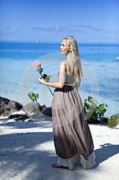 The woman with a rose in a hand looks at the sea