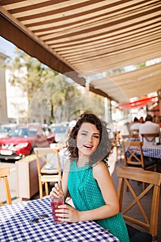 Woman in round sunglasses with cocktail at cafe terrace having fun