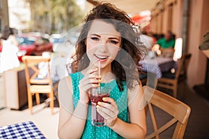 Woman in round sunglasses with cocktail at cafe terrace having fun