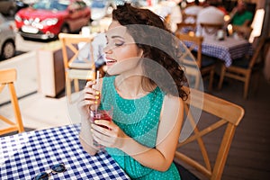 Woman in round sunglasses with cocktail at cafe terrace having fun