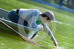 Woman in rowboat touching water