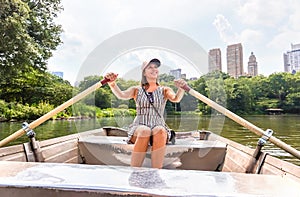 Woman rowing a rowboat and having fun in nature. Boating in summer. Smiling happy lady enjoying outdoor activity.