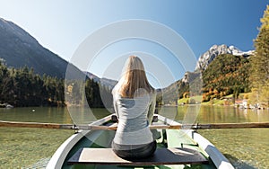 Woman is rowing with a rowing boat with a lake in the mountains