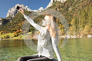 Woman is rowing with a rowing boat with a lake in the mountains