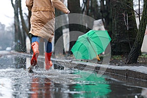 Woman in rubber boots running after umbrella on rainy day, closeup