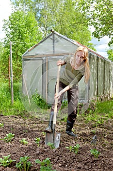 The woman in rubber boots with a shovel