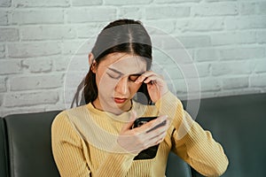 Woman rubbing eyes while using phone photo