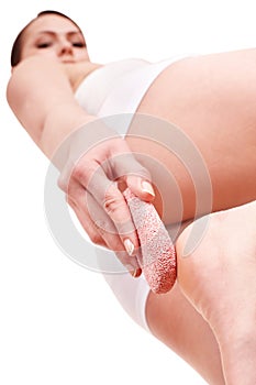 Woman rubbing heel of foot with pumice stone. photo