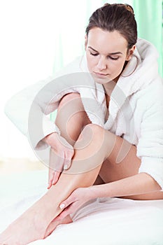 Woman rubbing lotion on her legs