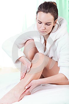 Woman rubbing lotion on her legs photo