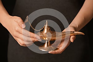 Woman rubbing magical Aladdin lamp, closeup