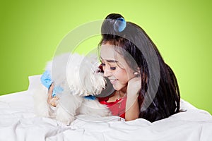 Woman rubbing nose with her Bolognese dog on a bed
