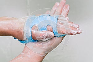 Woman rubs her hands with a blue washcloth. Hand washing with soap. White foam and hands close-up. Cleaning your hands with a