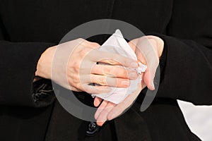 Woman rubs her hands with wet wipe