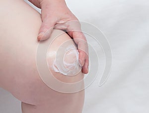 Woman rubs sore knee with anti-inflammatory ointment, close-up, medical, copy space photo