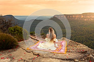 Woman on rug on mountain cliff with vsplendid iews