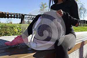 Woman rummaging in backpack after exercising outdoors in urban environment.