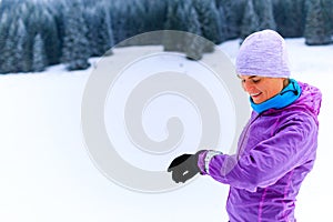 Woman runner checking sports watch on winter run