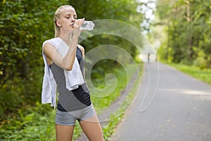 Woman runner drinking water after running