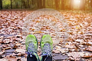 Woman runner foot in the fall leaves on the ground in the forest in autumn season