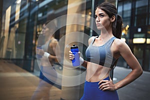 Woman runner is having a break and drinking water